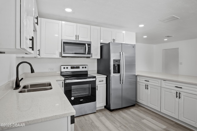 1324 Powers Ave, Holly Hill, FL 32117 - kitchen featuring appliances with stainless steel finishes, white cabinets, light wood finished floors, recessed lighting, and light stone counters