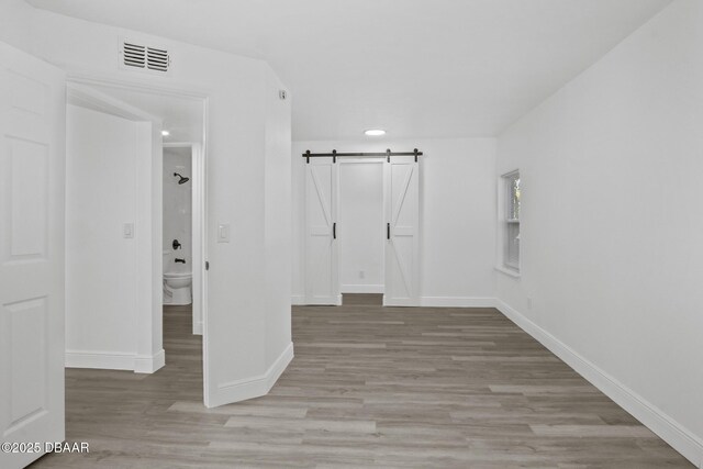 1324 Powers Ave, Holly Hill, FL 32117 - unfurnished bedroom featuring light wood-type flooring and a barn door
