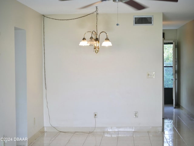 empty room with light tile patterned floors and ceiling fan with notable chandelier