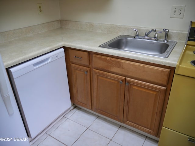 kitchen featuring white dishwasher, stove, light tile patterned floors, and sink