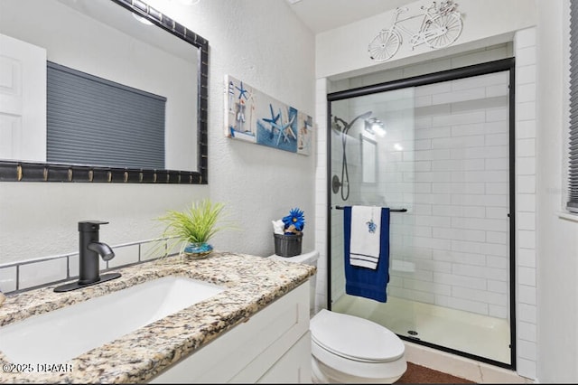 full bath with toilet, a shower stall, vanity, and a textured wall