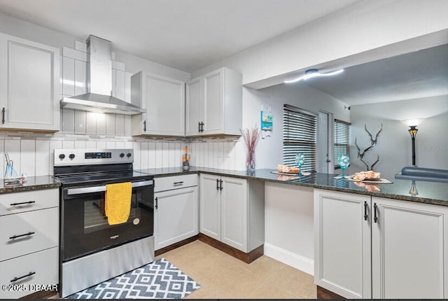 kitchen with electric range, wall chimney range hood, dark stone countertops, and tasteful backsplash