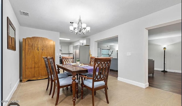 dining area featuring baseboards, visible vents, and a notable chandelier