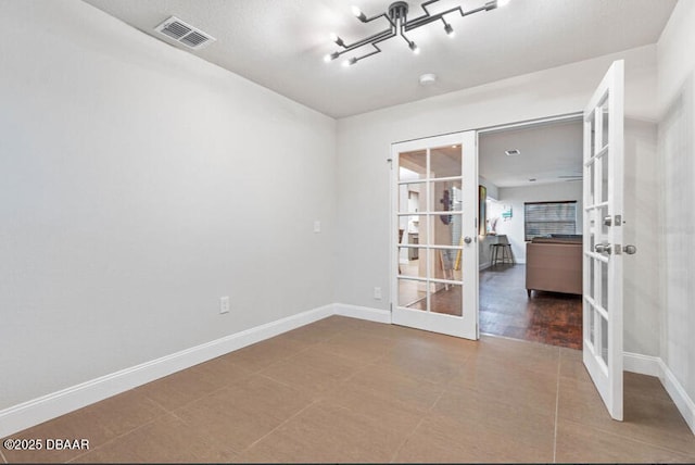 spare room with french doors, visible vents, and baseboards