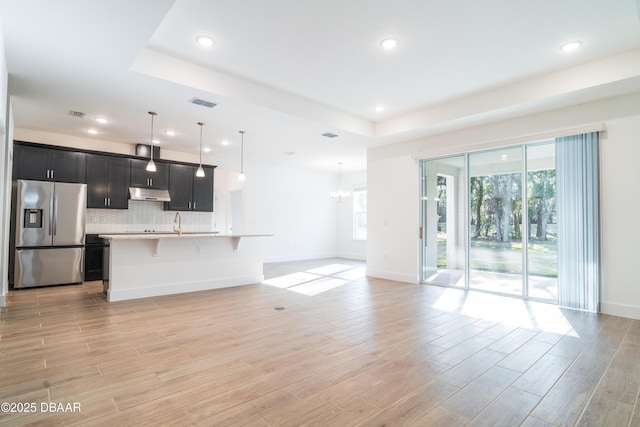 kitchen with pendant lighting, a tray ceiling, stainless steel fridge, and a breakfast bar