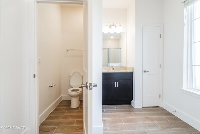 bathroom with plenty of natural light, toilet, a shower with door, and vanity