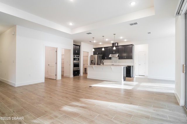 unfurnished living room with a tray ceiling and light hardwood / wood-style flooring