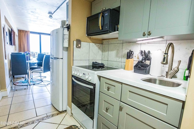 kitchen featuring tasteful backsplash, white appliances, light tile patterned floors, light countertops, and a sink