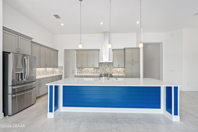 kitchen featuring stainless steel fridge, gray cabinets, decorative backsplash, a spacious island, and decorative light fixtures