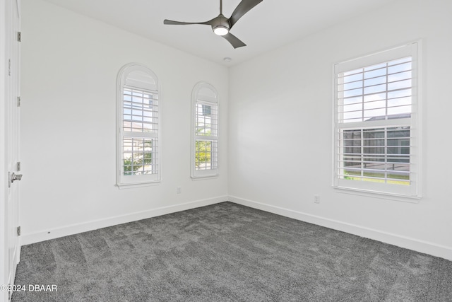 empty room featuring ceiling fan and dark colored carpet