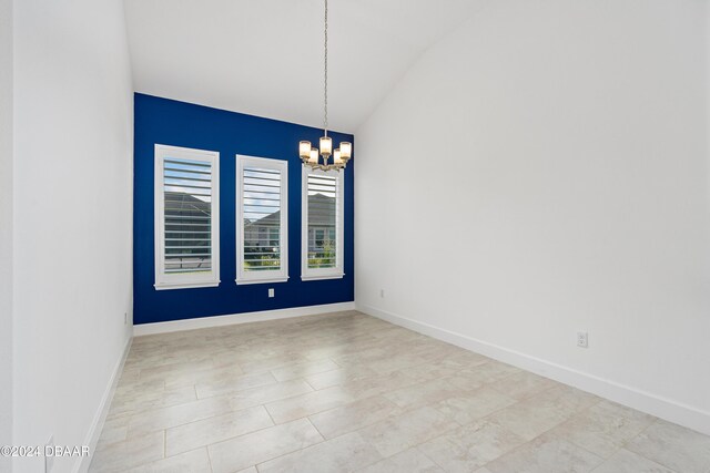 spare room featuring lofted ceiling and a notable chandelier