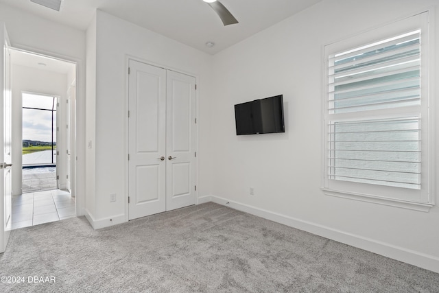 unfurnished bedroom with ceiling fan, a closet, and light carpet