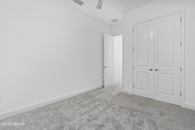 unfurnished bedroom with ceiling fan, light colored carpet, and a closet