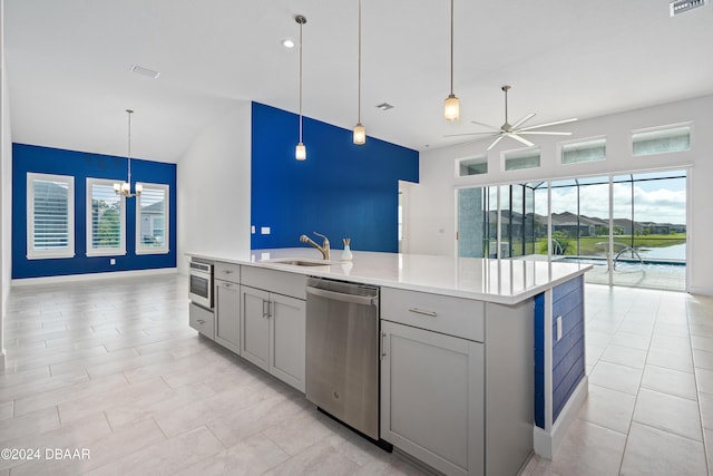 kitchen featuring decorative light fixtures, a center island with sink, sink, appliances with stainless steel finishes, and ceiling fan with notable chandelier