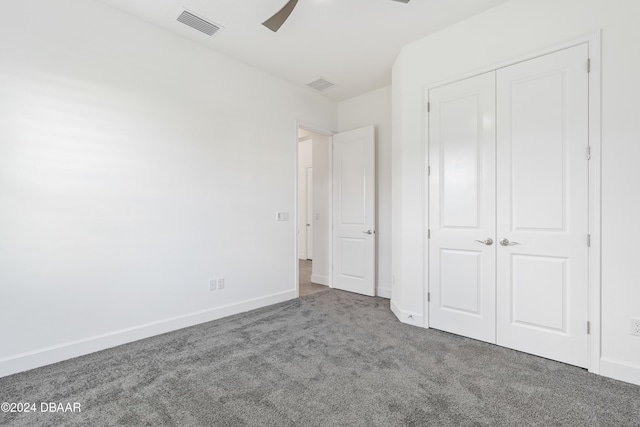 unfurnished bedroom with ceiling fan, a closet, and dark colored carpet