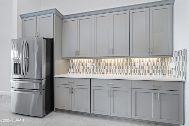 kitchen featuring gray cabinets, backsplash, and stainless steel fridge with ice dispenser