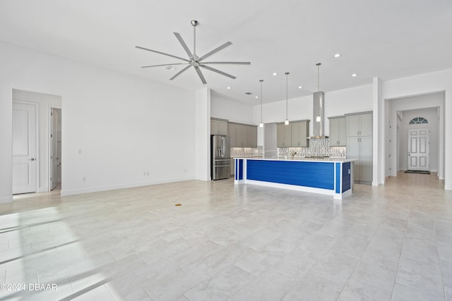 kitchen with ceiling fan, backsplash, a center island, stainless steel refrigerator with ice dispenser, and wall chimney exhaust hood