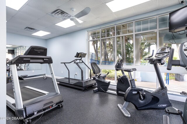 gym with a paneled ceiling, ceiling fan, and plenty of natural light