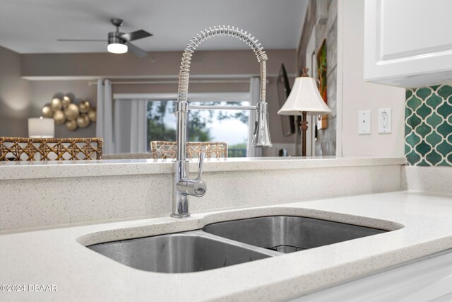 room details featuring light stone countertops, sink, ceiling fan, and white cabinets