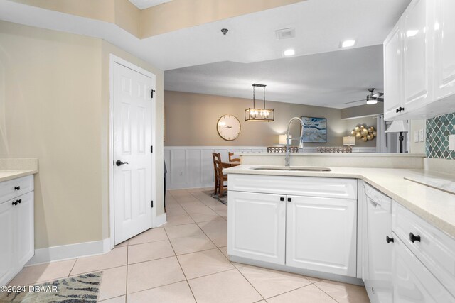 kitchen with white cabinetry, sink, kitchen peninsula, ceiling fan with notable chandelier, and pendant lighting