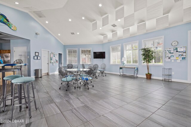 dining area featuring ornamental molding, high vaulted ceiling, plenty of natural light, and light tile patterned floors