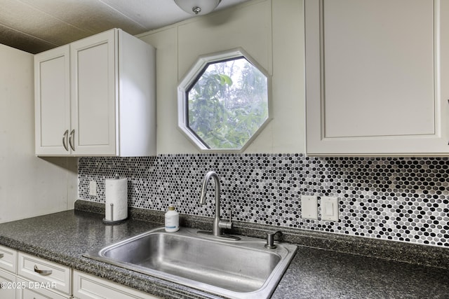 1420 Carol Lee St, Daytona Beach, FL 32117 - kitchen featuring a sink, dark countertops, white cabinetry, and decorative backsplash