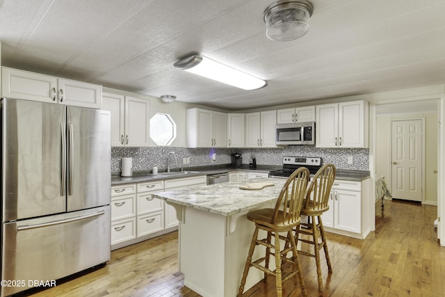 1420 Carol Lee St, Daytona Beach, FL 32117 - kitchen featuring stainless steel appliances, a sink, light wood finished floors, a kitchen breakfast bar, and tasteful backsplash