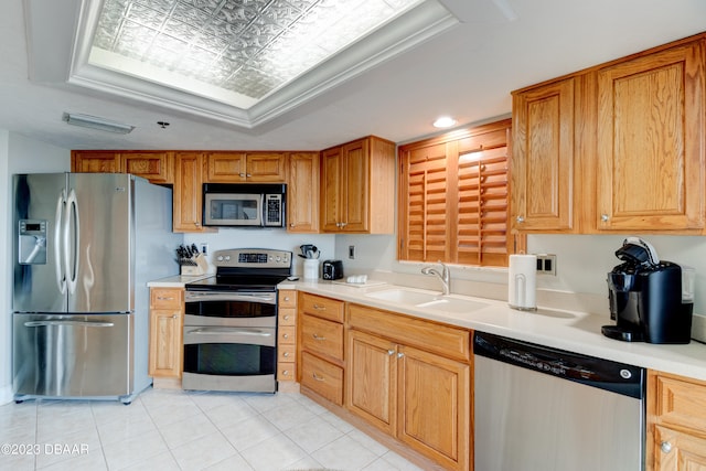 kitchen featuring light tile patterned flooring, sink, appliances with stainless steel finishes, and a tray ceiling