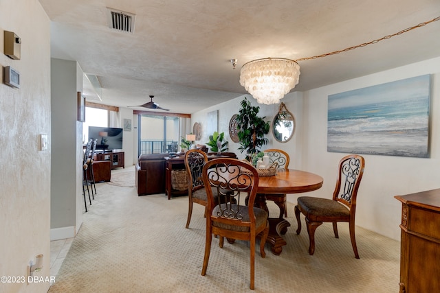 carpeted dining area with a textured ceiling and ceiling fan with notable chandelier