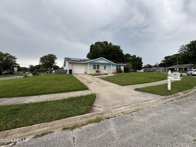 view of front facade with a garage, solar panels, and a front yard