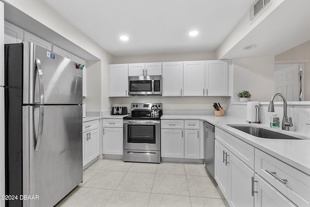 kitchen with white cabinets, appliances with stainless steel finishes, sink, and light tile patterned floors