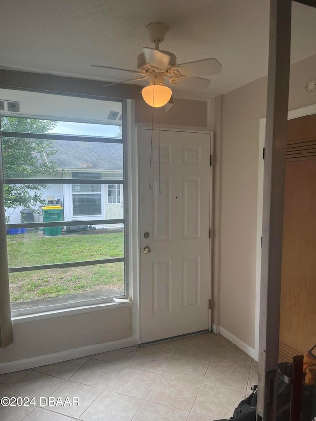 tiled foyer with ceiling fan and plenty of natural light