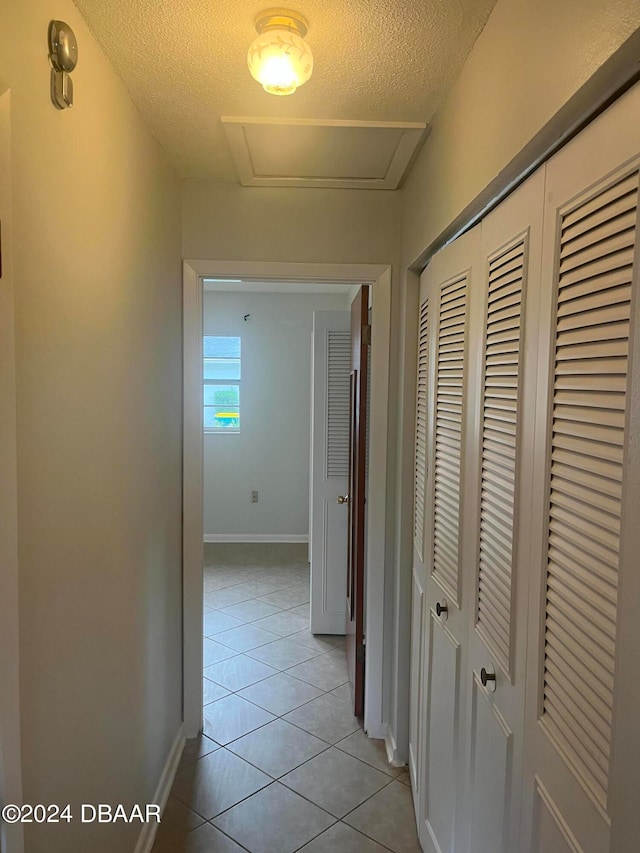 corridor with a textured ceiling and light tile patterned flooring