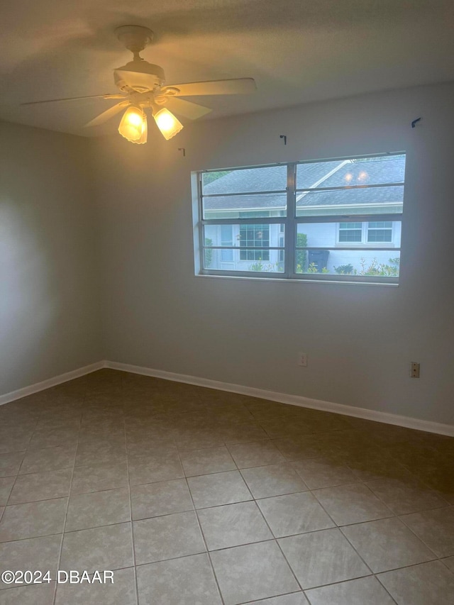 tiled empty room featuring ceiling fan and a healthy amount of sunlight