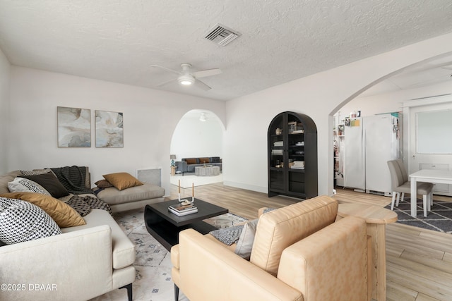 25 Dolphin Ave, Ormond Beach, FL 32176 - living room with arched walkways, light wood finished floors, a ceiling fan, and a textured ceiling