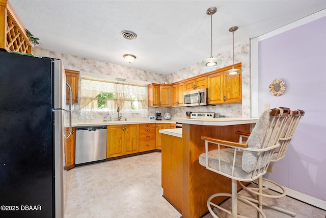 22 N St Andrews Dr, Ormond Beach, FL 32174 - kitchen featuring appliances with stainless steel finishes, a peninsula, a breakfast bar area, light countertops, and brown cabinetry