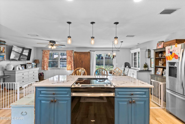 kitchen featuring stainless steel refrigerator with ice dispenser, blue cabinets, a kitchen island with sink, and range with electric stovetop