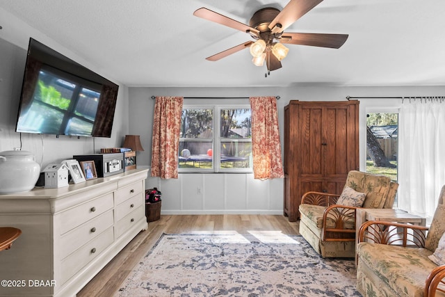 living area with ceiling fan and light hardwood / wood-style flooring