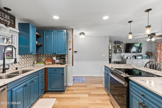 kitchen featuring sink, stainless steel appliances, light stone countertops, blue cabinetry, and light wood-type flooring