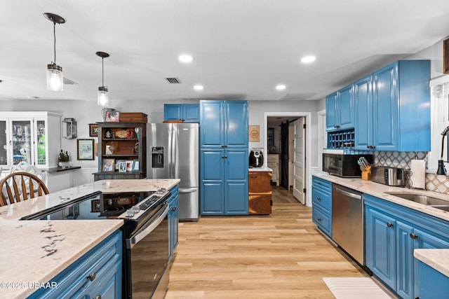 kitchen featuring stainless steel appliances, pendant lighting, and blue cabinets