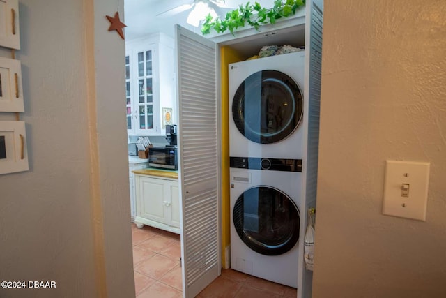 laundry room featuring stacked washer / drying machine and light tile patterned flooring