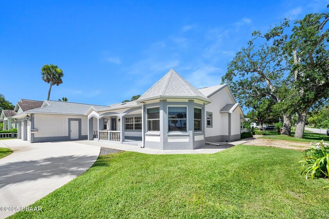 1650 Riverside Dr, Holly Hill, FL 32117 - view of front facade featuring stucco siding, a front yard, a porch, and concrete driveway