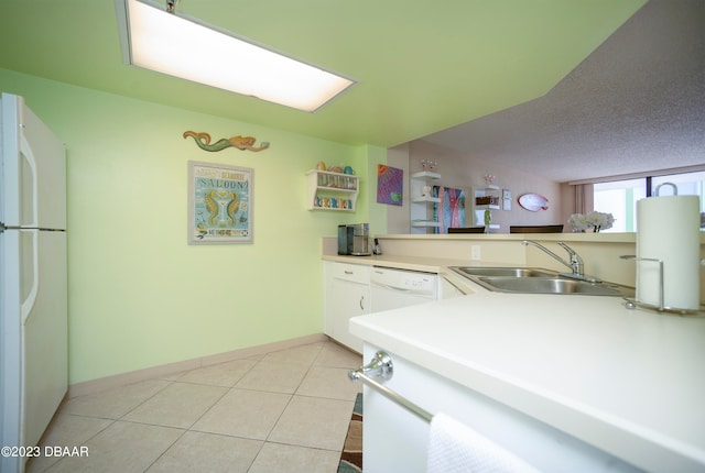 kitchen featuring a textured ceiling, sink, white appliances, and light tile patterned floors