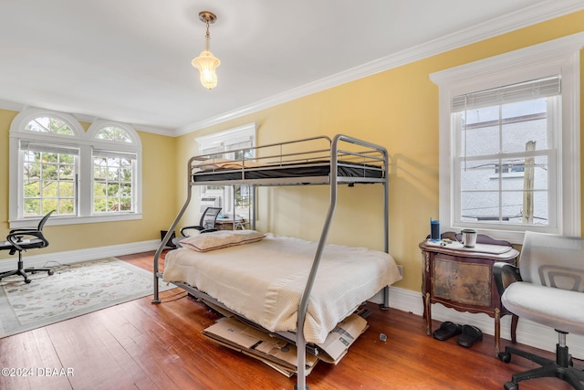 bedroom featuring hardwood / wood-style floors, multiple windows, and crown molding