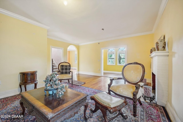 living area with a brick fireplace, ornamental molding, and light hardwood / wood-style flooring