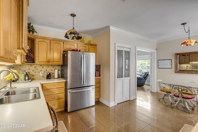 kitchen featuring tasteful backsplash, ornamental molding, stainless steel fridge, decorative light fixtures, and sink