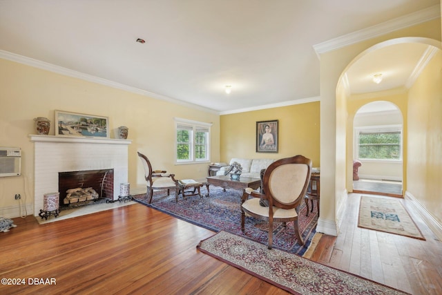 living room featuring crown molding, hardwood / wood-style flooring, a healthy amount of sunlight, and a fireplace