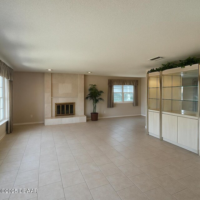2944 Ocean Shore Blvd, Ormond Beach, FL 32176 - unfurnished living room with a textured ceiling, light tile patterned floors, baseboards, and a tile fireplace