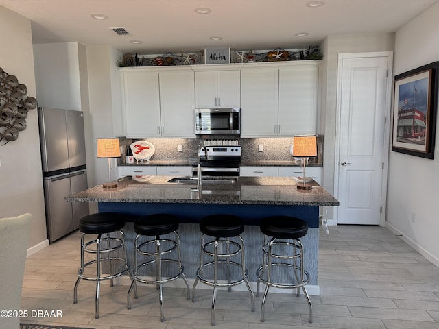 168 Ocean Hammock Loop, Daytona Beach, FL 32124 - kitchen with stainless steel appliances, a sink, tasteful backsplash, white cabinets, and a breakfast bar area