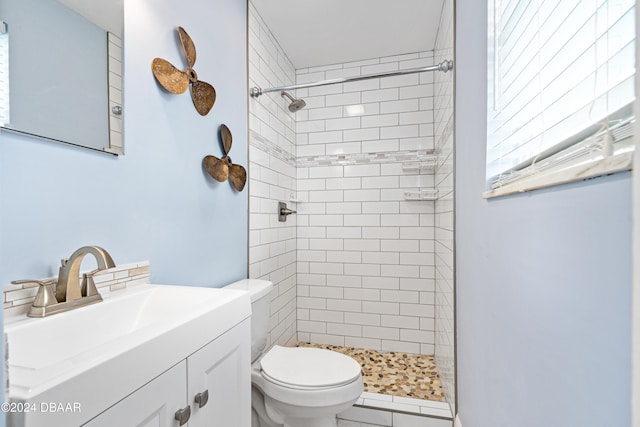 bathroom featuring vanity, toilet, and tiled shower